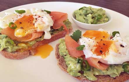 Avocado on toasted rye bread with salmon and poached egg