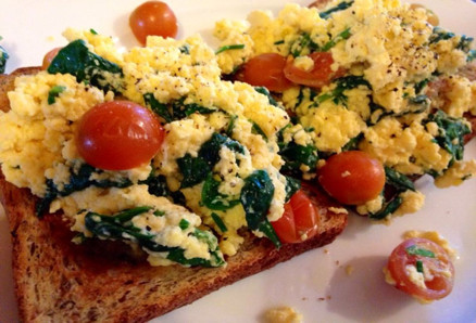 Scrambled eggs with toasted rye, spinach and tomatoes